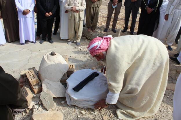 One of the clergymen in Sinjar places holy dirt on the site of the shrine to bless it, 2020.